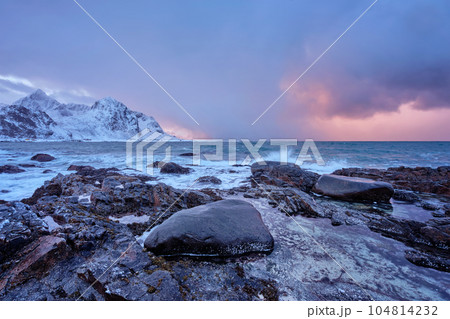 Beach of Norwegian sea on rocky coast in fjord on sunset in winter. Vareid beach, Lofoten islands, Norway Beach of Norwegian sea on rocky coast in fjord on sunset in winter. Vareid beach, Lofoten islands, Norway 104814232