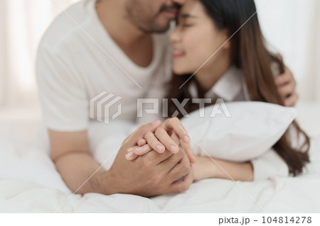 Asian Romantic couple in bed enjoying sensual foreplay Happy sensual young couple lying in bed together. Beautiful loving couple kissing in bed Asian Romantic couple in bed enjoying sensual foreplay Happy sensual young couple lying in bed together. Beautiful loving couple kissing in bed 104814278
