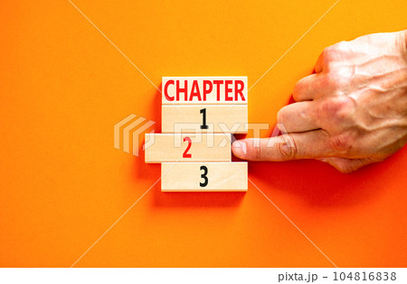 Time to chapter 2 symbol. Concept word Chapter 1 2 3 on wooden block. Businessman hand. Beautiful orange table orange background. Business planning and time to chapter 2 concept. Copy space. 104816838