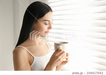 Young woman with cup of tea near window. Lazy morning Young woman with cup of tea near window. Lazy morning 104817042