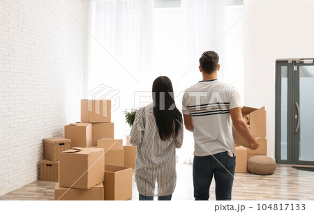 Couple in room with cardboard boxes on moving day 104817133