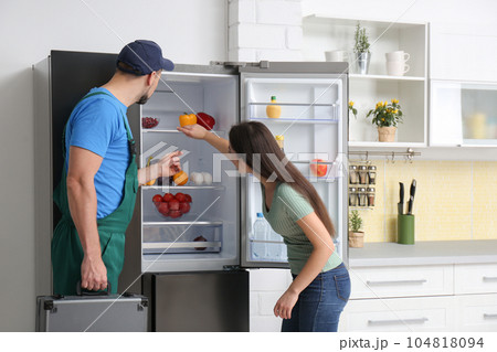 Male technician talking with client near refrigerator in kitchen Male technician talking with client near refrigerator in kitchen 104818094