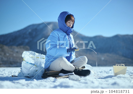冬の湖でワカサギ釣りをする20代女性 冬の湖でワカサギ釣りをする20代女性 104818731