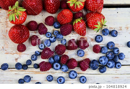 Healthy mixed fruit and ingredients with strawberry, raspberry, blueberry from top view. Berries on rustic white wooden background 104818924