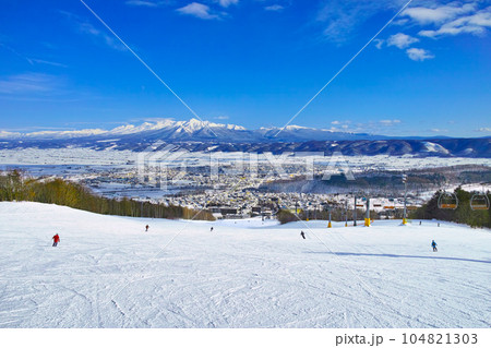 快晴の富良野スキー場から見る十勝岳連峰、北の峰ゾーンの広大な初心者コースを滑るスキーヤー達 快晴の富良野スキー場から見る十勝岳連峰、北の峰ゾーンの広大な初心者コースを滑るスキーヤー達 104821303