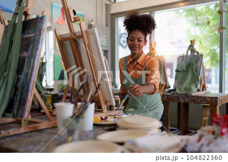 Beautiful american african artist woman painting in art studio at the university classroom 104822360