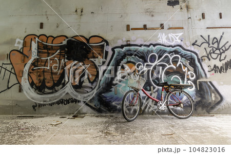 A red bicycle is parked beside the graffiti patterns on the wall. A red bicycle is parked beside the graffiti patterns on the wall. 104823016