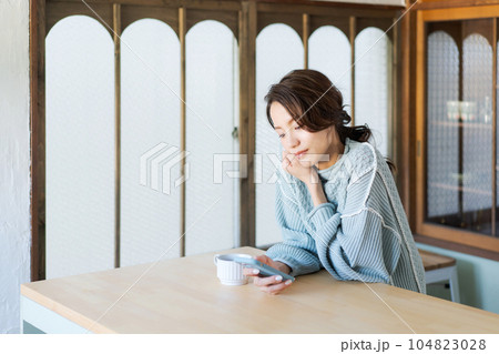 スマホを見るニットを着た女性の写真 104823028