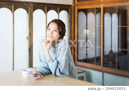 スマホを見るニットを着た女性の写真 104823031