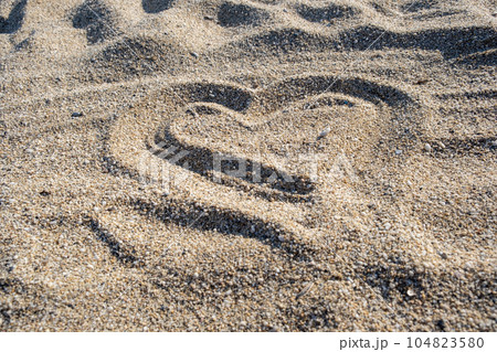 Drawing heart shape love concept on sand at the beach with vacation holiday summer travel background. Heart shape and footprint on sand. Drawing heart shape love concept on sand at the beach with vacation holiday summer travel background. Heart shape and footprint on sand. 104823580