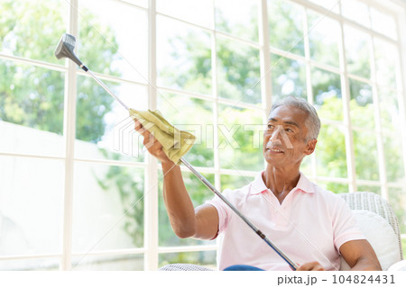 リビングでコルフクラブを磨くシニアの男性 104824431
