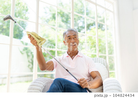 リビングでコルフクラブを磨くシニアの男性 104824434