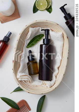 A dropper bottle and pump bottle without label are placed inside a basket. Other bottles with a candle and wooden comb displayed. Branding mockup A dropper bottle and pump bottle without label are placed inside a basket. Other bottles with a candle and wooden comb displayed. Branding mockup 104830516