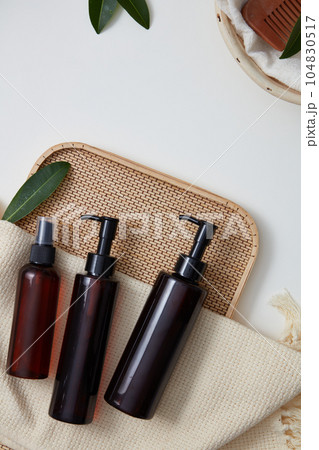 Bamboo tray with three empty label bottles and a wool scarf placed on. Promoting cleanser, shampoo, foams or lotion products Bamboo tray with three empty label bottles and a wool scarf placed on. Promoting cleanser, shampoo, foams or lotion products 104830517