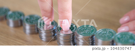 Businesswoman fingers walking on pile of coins at desk. Businesswoman fingers walking on pile of coins at desk. 104830747