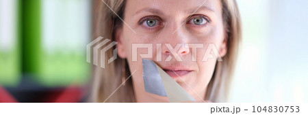 Woman removes adhesive tape covering her mouth. Woman removes adhesive tape covering her mouth. 104830753