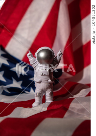 Plastic toy figure astronaut on American flag background Copy space. 50th Anniversary of USA Landing on The Moon Concept of out of earth travel, private spaceman commercial flights missions and 104831202