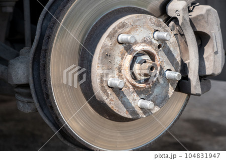 Disc brake of the vehicle for repair, in process of new tire replacement. Car brake repairing in garage. Replacement of brake pads. Suspension of car for maintenance brakes and shock absorber systems. Disc brake of the vehicle for repair, in process of new tire replacement. Car brake repairing in garage. Replacement of brake pads. Suspension of car for maintenance brakes and shock absorber systems. 104831947