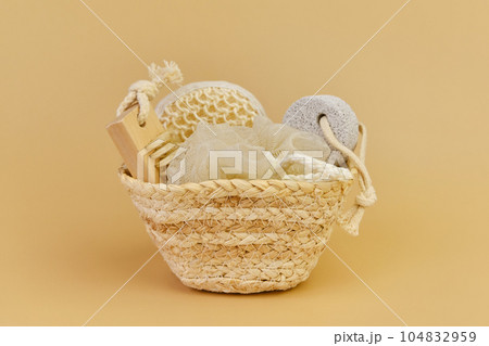 Bath accessories set in wicker basket on a beige background. 104832959