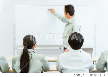 会議室で講習・セミナーを受ける作業着姿の男女の後ろ姿 会議室で講習・セミナーを受ける作業着姿の男女の後ろ姿 104833124