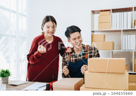 A young Asian couple shows delight and smiles on their faces when they see the sales volume and customer orders exceed expectations. sme or small business family concepts. A young Asian couple shows delight and smiles on their faces when they see the sales volume and customer orders exceed expectations. sme or small business family concepts. 104835660