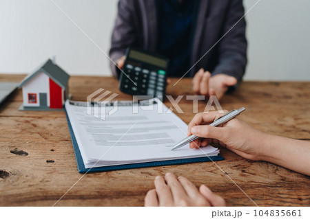 Guarantee, mortgage, contract, contract, signed, real estate agent or bank officer holding a calculator, submits a bid with a customer to buy a home before signing to make a deal. Guarantee, mortgage, contract, contract, signed, real estate agent or bank officer holding a calculator, submits a bid with a customer to buy a home before signing to make a deal. 104835661