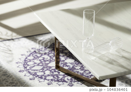 This room has a calm atmosphere with natural light. There are clay pots, glass bottles, coffee and various objects on the table. 104836401
