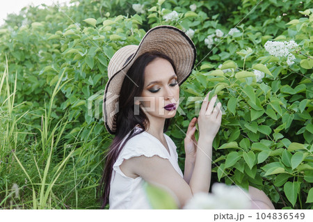A fashionable girl with dark hair, a spring portrait in lilac tones in summer. Bright professional makeup. 104836549