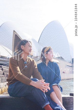 シドニーのオペラハウスの前で仲良く座る日本人カップル 104841844