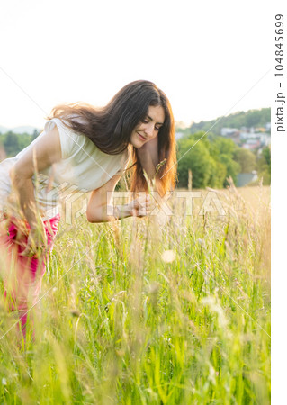 A young woman walks across a field. A walk in nature in the summer. 104845699
