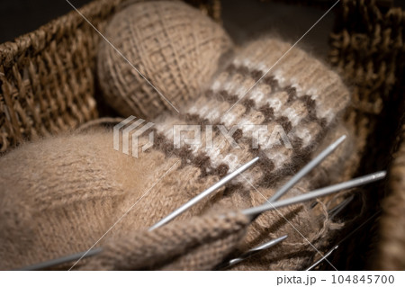 Needlework in a wicker basket: knitting wool socks. Needlework in a wicker basket: knitting wool socks. 104845700