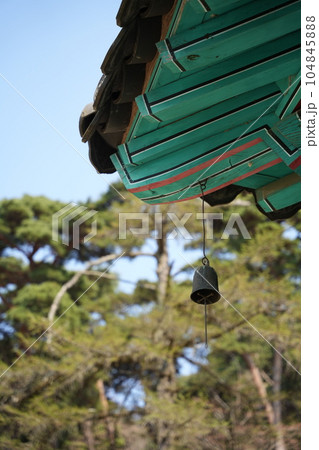 There is a bell on the roof of the temple and the blue sky and nature are combined. 104845888