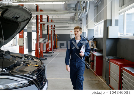 Professional handsome male car mechanic walking along service station Professional handsome male car mechanic walking along service station 104846082
