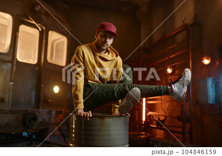 Young male breakdancer dancing on steel barrel tank 104846159