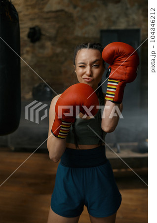 Attractive female boxer looking through red boxing gloves Attractive female boxer looking through red boxing gloves 104846212