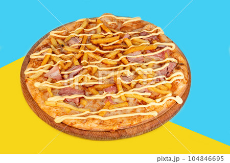 Pizza with bacon cheese and herbs on a wooden plate with cheese and cherry tomatoes. On a colored Pizza with bacon cheese and herbs on a wooden plate with cheese and cherry tomatoes. On a colored 104846695