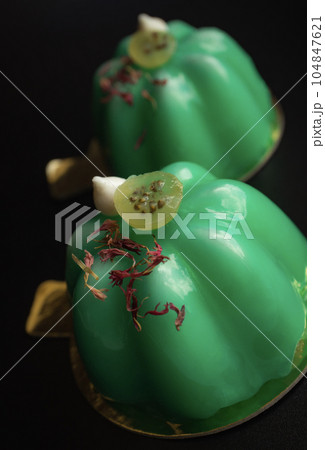 Green gooseberry mousse modern desserts with mirror glaze topped with meringue kisses and berries on black background close up 104847621