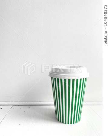 Green striped coffee cup, vertical photo. Street food coffee to go, closed plastic cup for various drinks and beverages on white background. Single object, take away 104848275