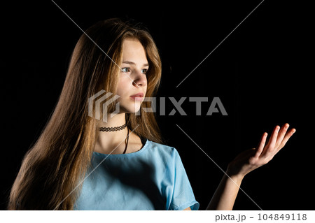 Close-up of a bust of a long-haired girl against a black background. 104849118