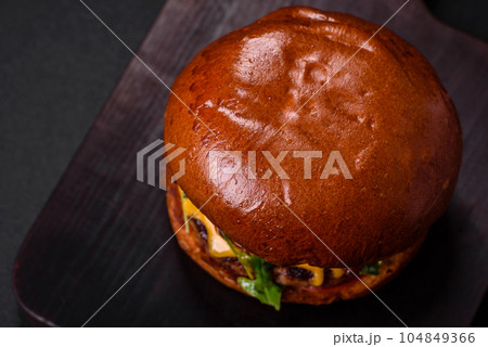 Burger with juicy beef cutlet, cheese, tomatoes, salt, spices and herbs Burger with juicy beef cutlet, cheese, tomatoes, salt, spices and herbs 104849366