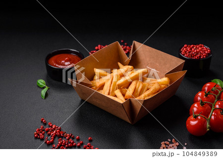 Delicious crispy french fries with salt and spices in a cardboard box 104849389