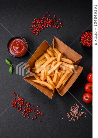 Delicious crispy french fries with salt and spices in a cardboard box 104849391