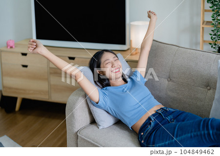 Home lifestyle woman relaxing sleeping on sofa patio living room. Happy lady lying down on comfortable pillows taking a nap for wellness and health. Tropical vacation Home lifestyle woman relaxing sleeping on sofa patio living room. Happy lady lying down on comfortable pillows taking a nap for wellness and health. Tropical vacation 104849462