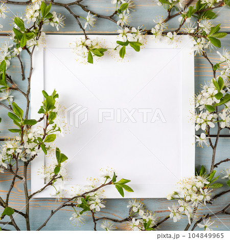 Mockup for special offers as advertising or other ideas. Fresh branches of cherry white blossoms and white empty frame on blue wooden table. Empty place for inspirational, motivational text or quote. Mockup for special offers as advertising or other ideas. Fresh branches of cherry white blossoms and white empty frame on blue wooden table. Empty place for inspirational, motivational text or quote. 104849965