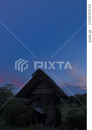 北杜市武川町、水車小屋の上、夕焼け雲の中に浮かぶ月齢5.9の月 104850419