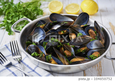 Clams mussels in a stainless steel bowl with lemon and herbs. Shellfish seafood. 104850752