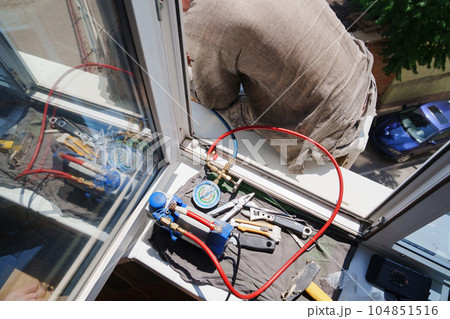 without a face. A man installs an external air conditioner. dangerous work. 104851516