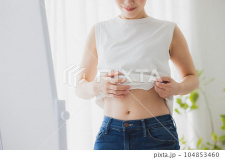 鏡でお腹をチェックする女性 鏡でお腹をチェックする女性 104853460