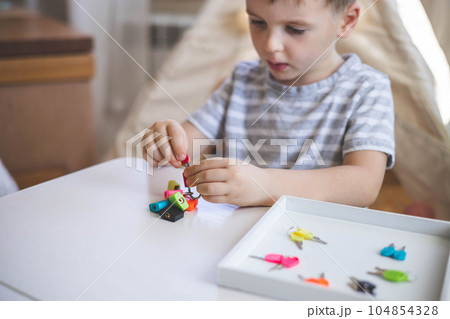 The child works with Montessori material with colored locks. Picks up keys. Develops fine motor skills. 104854328