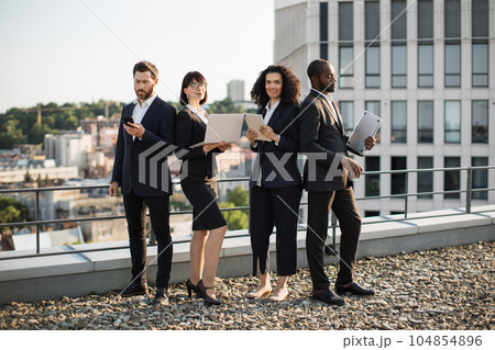 Corporate partners operating modern gadgets on rooftop 104854896